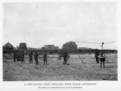 A LIFE-SAVING CREW DRILLING WITH BEACH APPARATUS Hauling in a breeches-buoy and a passenger.