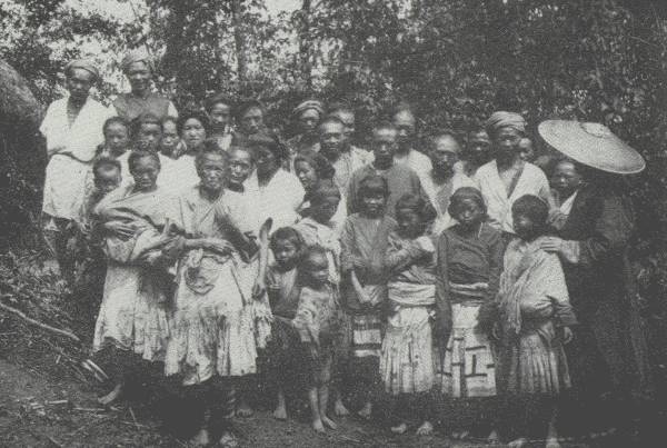 FAR FROM THE MADDENING THRONG  Regimenting the whole village to bid a sad farewell; Samuel Pollard, author's traveling companion on this trip in the wilds, stands under the hat on the right.