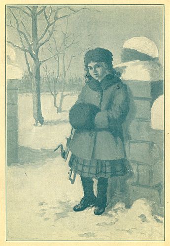 Girl standing against brick fence holding a muff