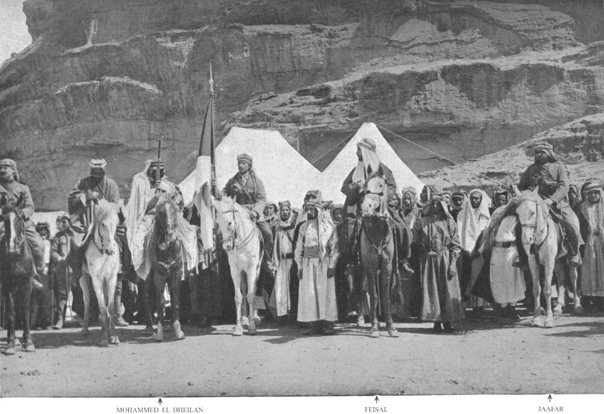 Photo wide shot of men standing and on horses facing
                forward; Mohammed el Dheilan, Feisal, and Jaafar
                indicated